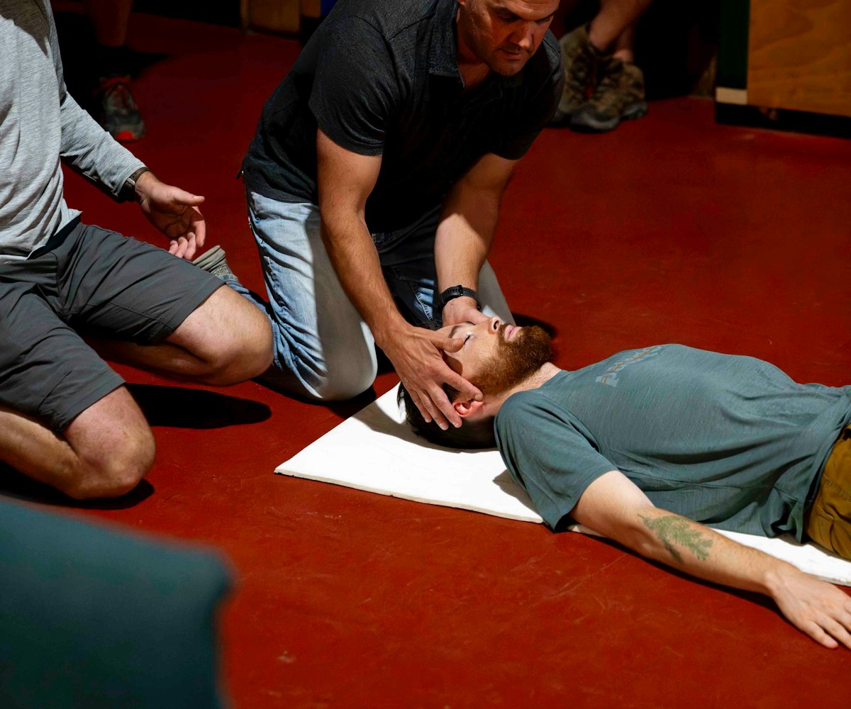 An instructor guides a first aid trainee through a recovery position during a course